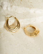 Gold chunky hoop minimalist earrings on a textured surface