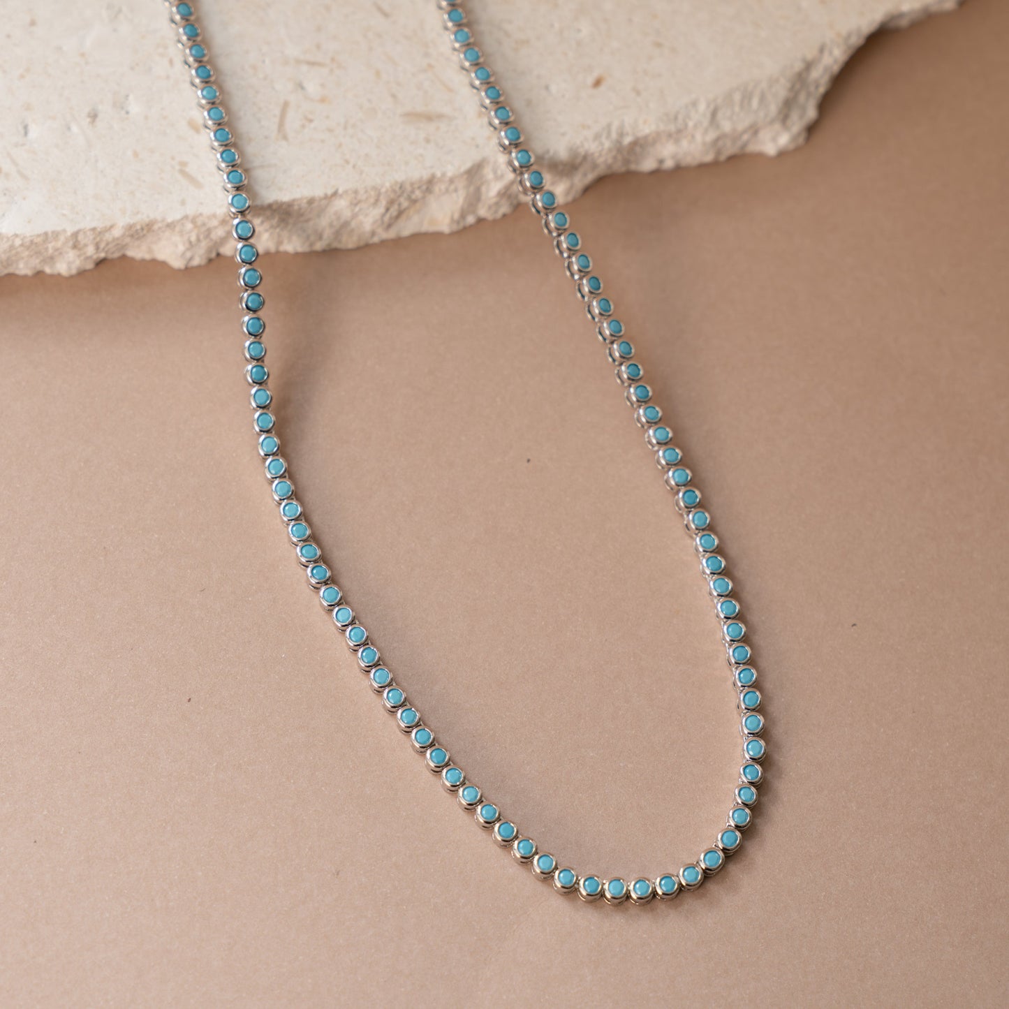 closeup image of turquoise jewelry featuring a dainty silver tennis necklace