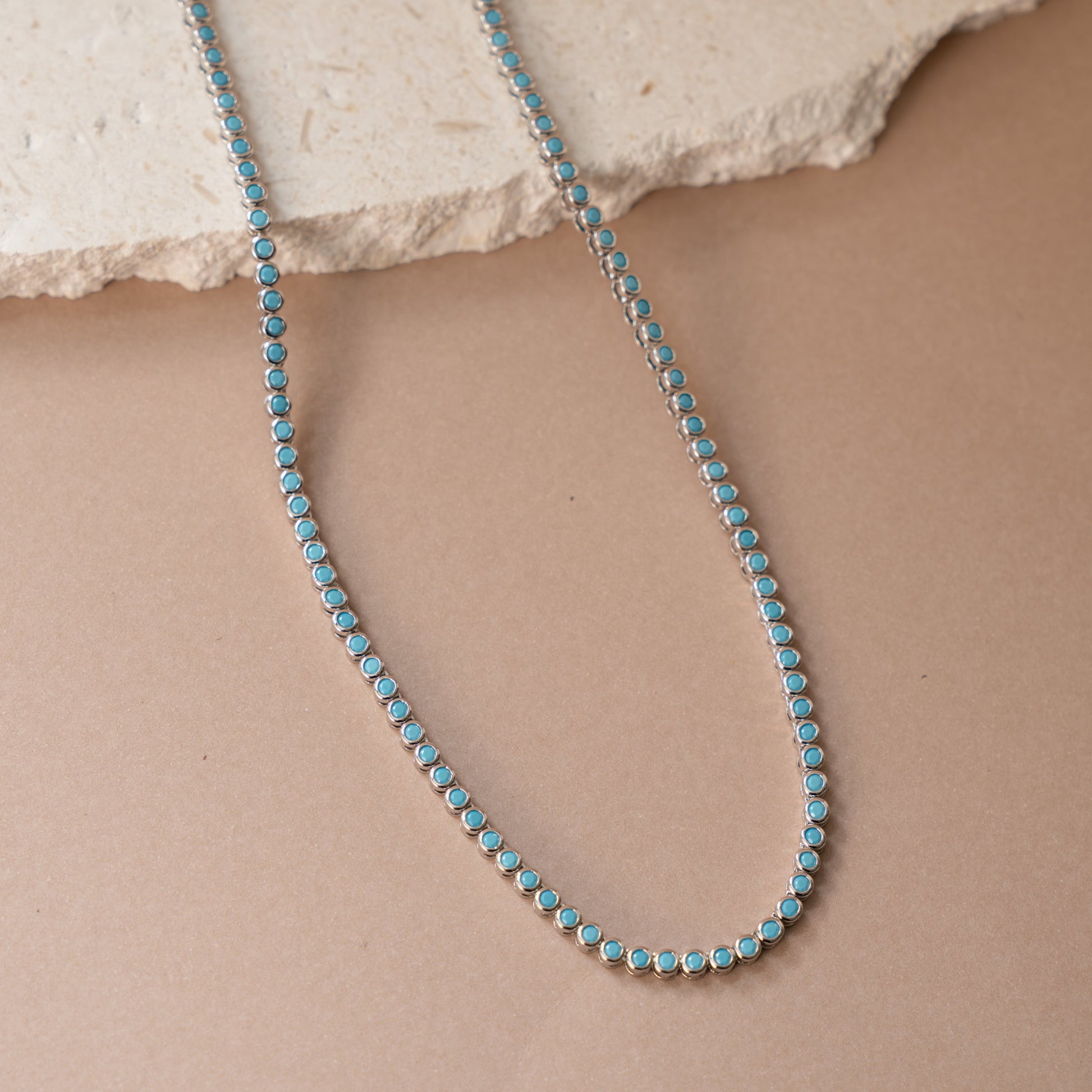 closeup image of turquoise jewelry featuring a dainty silver tennis necklace