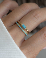 model wearing an eternity stackable ring with tiny turquoise stones, and a matching turquoise ring with dainty cubic zirconia stones and a baguette cut center turquoise stone