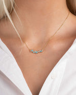 model wearing gold bar necklace with a turquoise and cubic zirconia beaded necklace design 