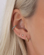 model wearing gold twisted hoop earrings, diamond stud earrings in gold, dainty gold ball stud earring, turquoise ear cuff