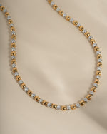 Gold and silver beaded diamond necklace on a beige background
