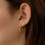 Model wearing minimalist gold twisted hoops
