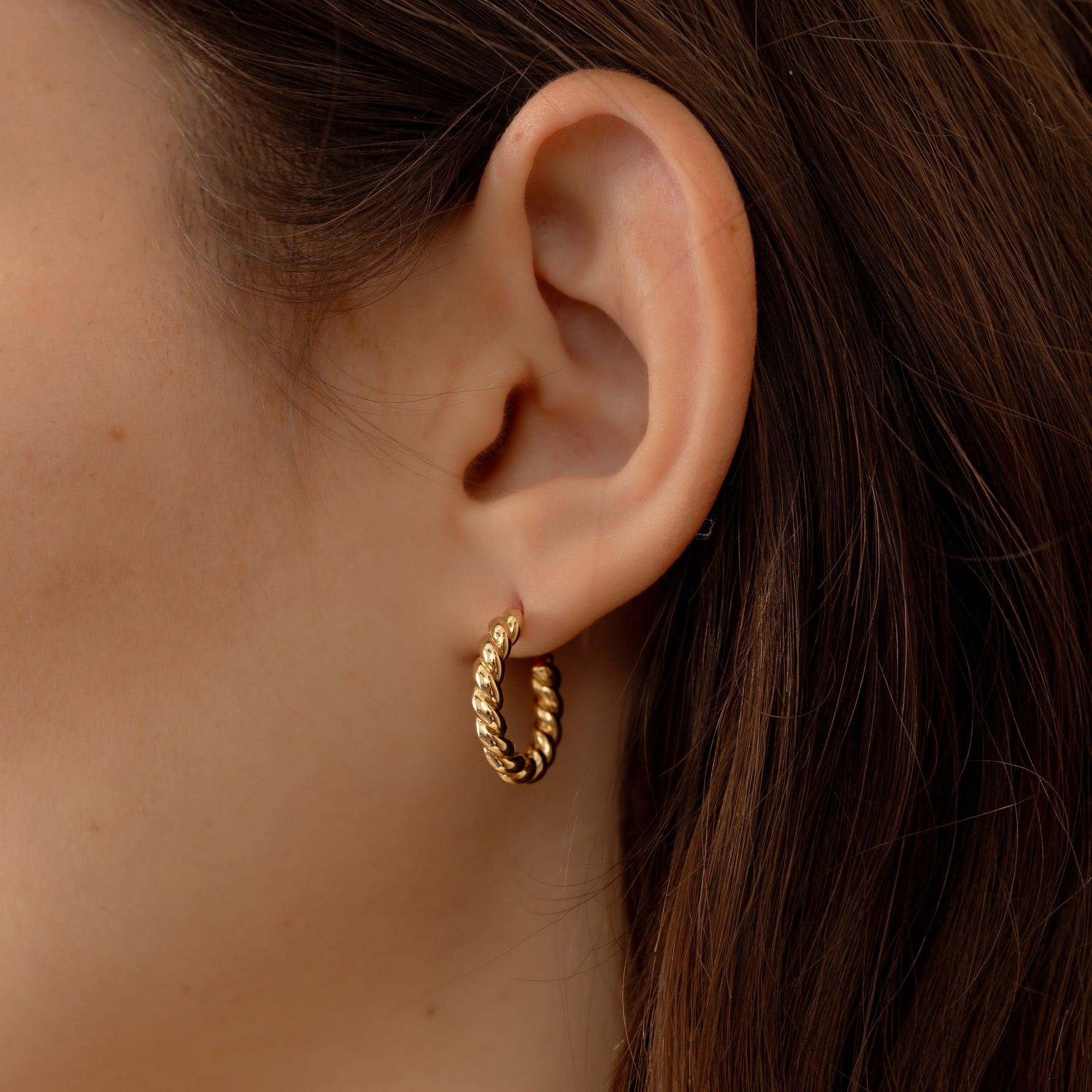 Model wearing minimalist gold twisted hoops