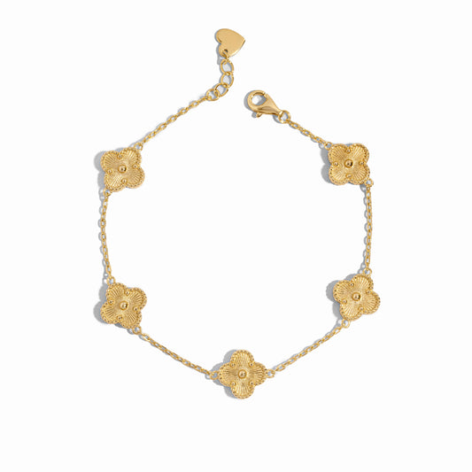 Close-up of a gold clover jewelry charm bracelet highlighting fine detailing.