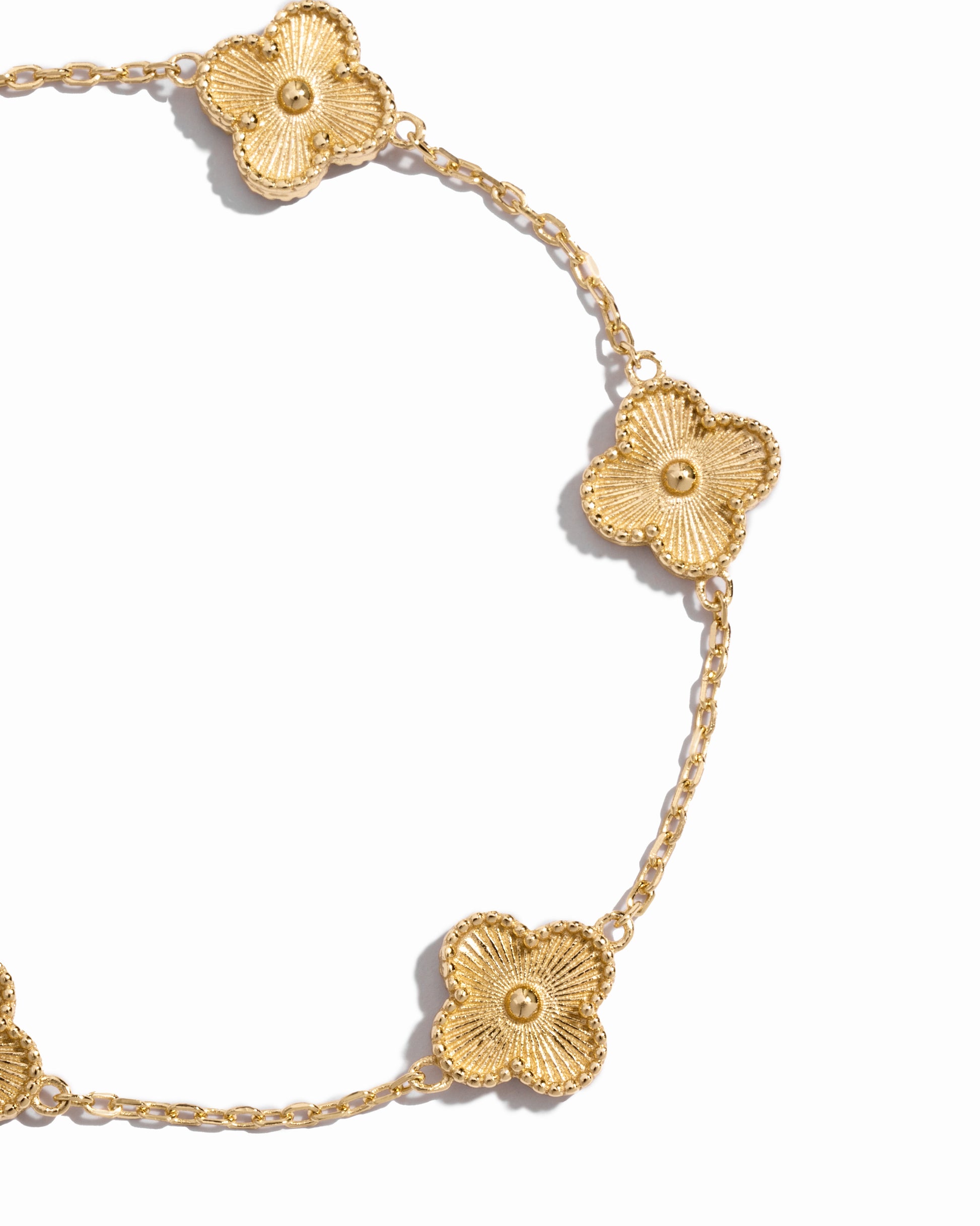 closeup image of four leaf clover design on gold chain bracelet