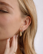 Model wearing gold statement hoops, cz huggie hoops, and a diamond stud earring on model 