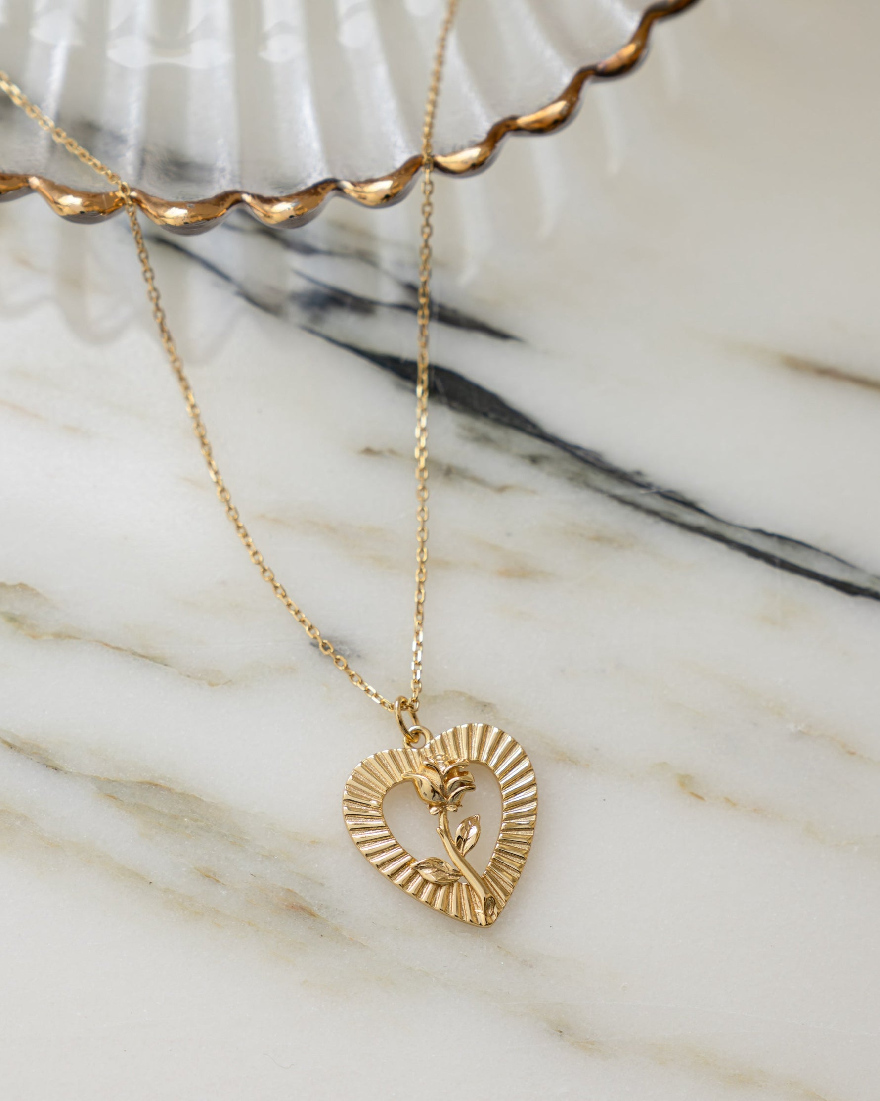 Gold chain vintage necklace with a heart pendant on a marble background 