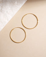 40mm gold hoop earrings photographed overhead, minimalist design with timeless appeal.