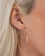 Close-up of large gold hoops on model, the ultimate statement hoop earrings that still feel light and comfortable.
