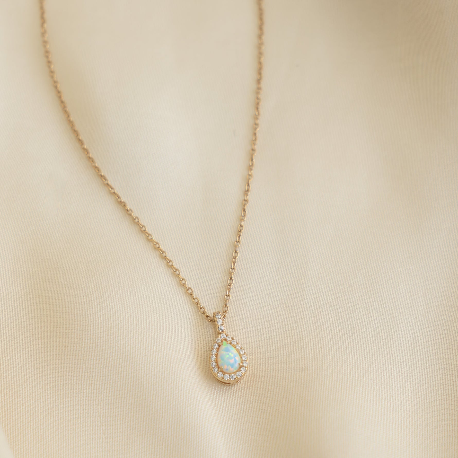 Closeup image of opal necklace with dainty diamonds and 14k gold plating