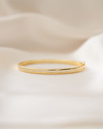 Gold minimalist bangle bracelet on a silk background