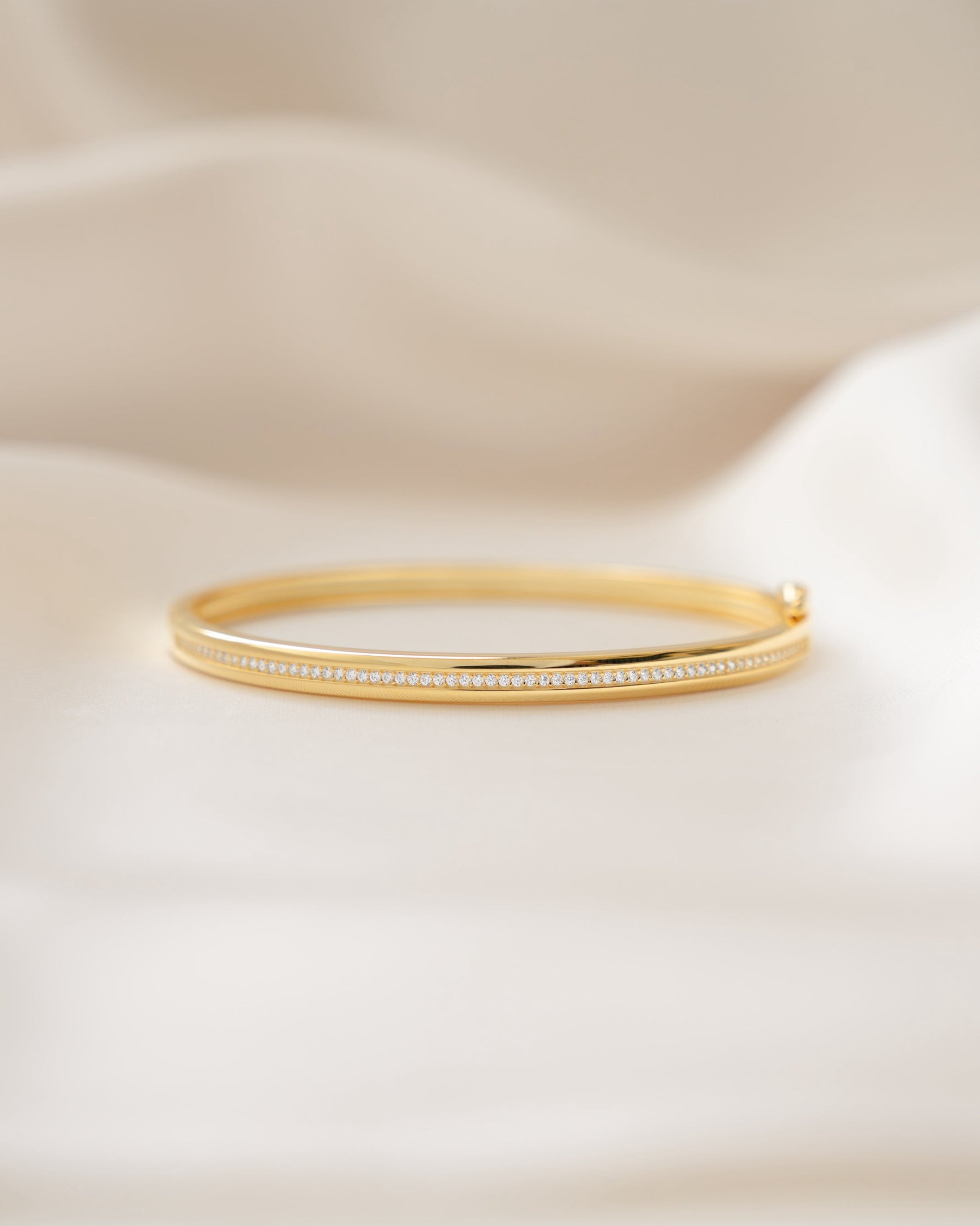 Gold minimalist bangle bracelet on a silk background