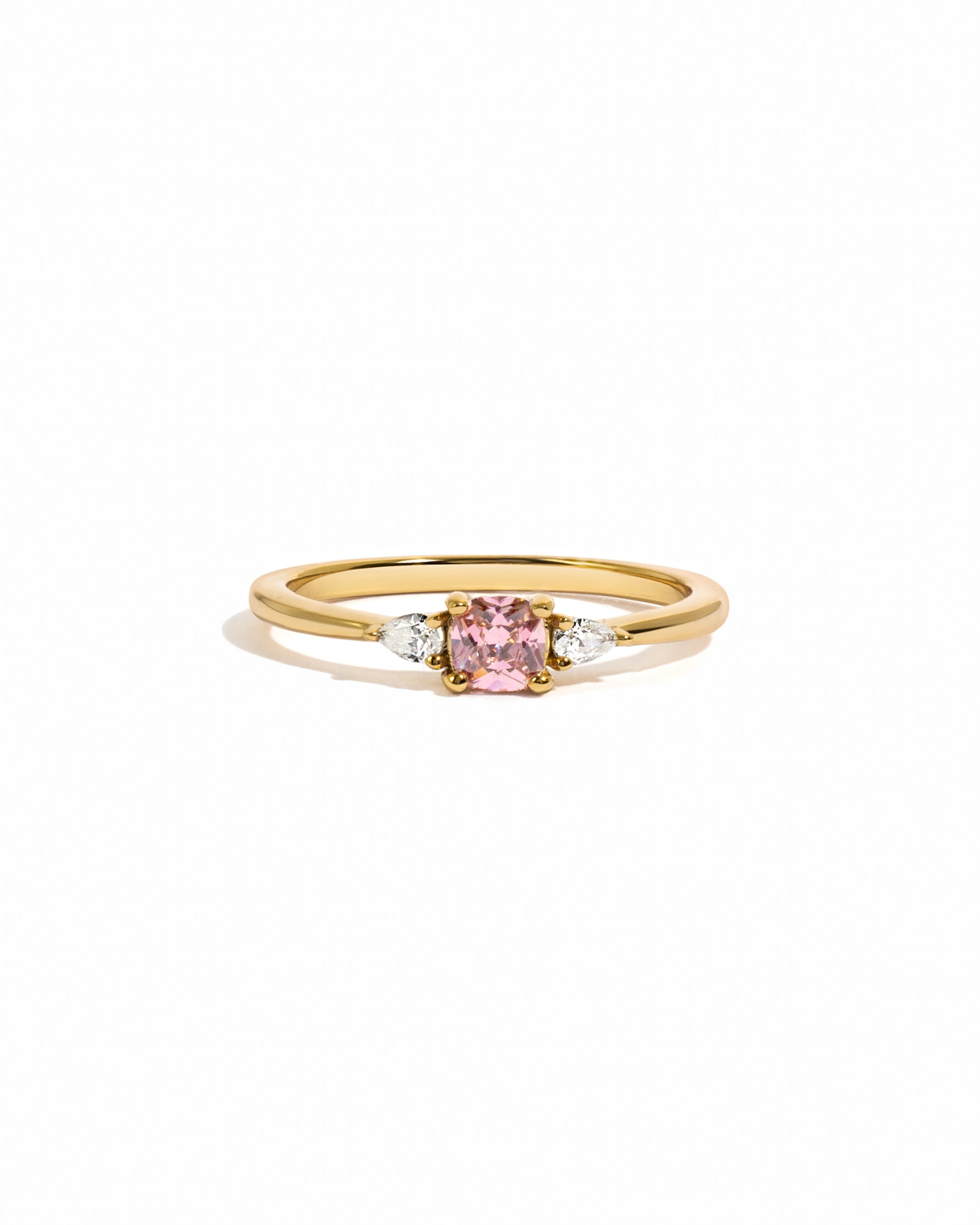 Gold ring with a pink cushion gemstone and smaller cz diamonds on a white background