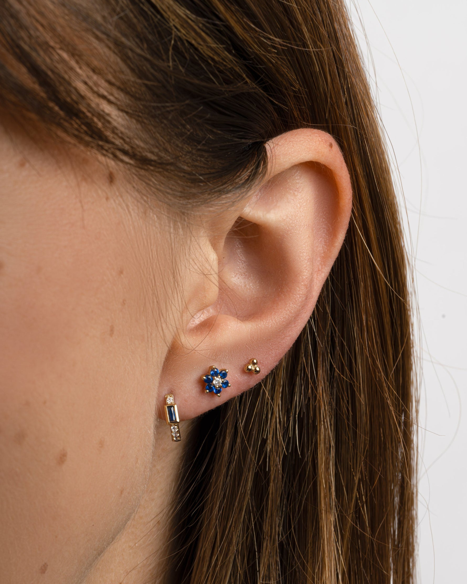 Sami Jewels Sapphire Baguette Huggie Earrings in gold with sparkling rectangular sapphires, worn by a model.