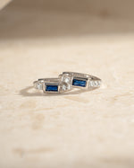 Close-up of Sami Jewels sapphire baguette huggie earrings in sterling silver, showcasing their sparkling blue sapphires and sleek design.