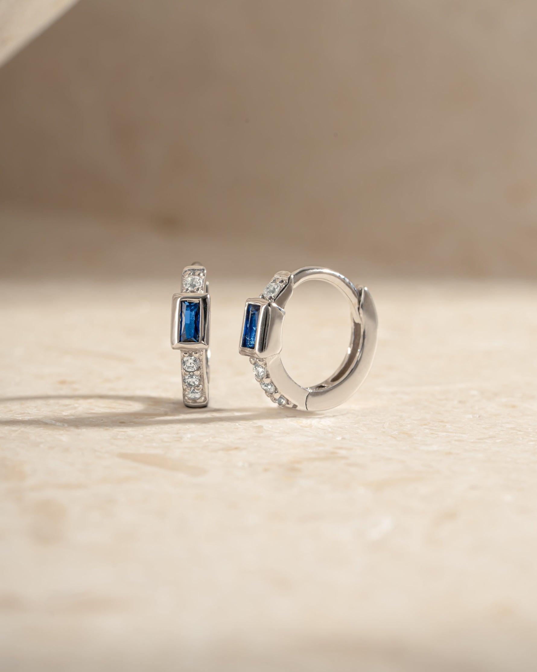 Sterling silver Sapphire Baguette Huggie Earrings with side view, showcasing sparkling blue sapphires and sleek hoop design.
