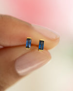 Close-up of sapphire baguette stud earrings by Sami Jewels, featuring elegant gold settings and sparkling blue sapphires.
