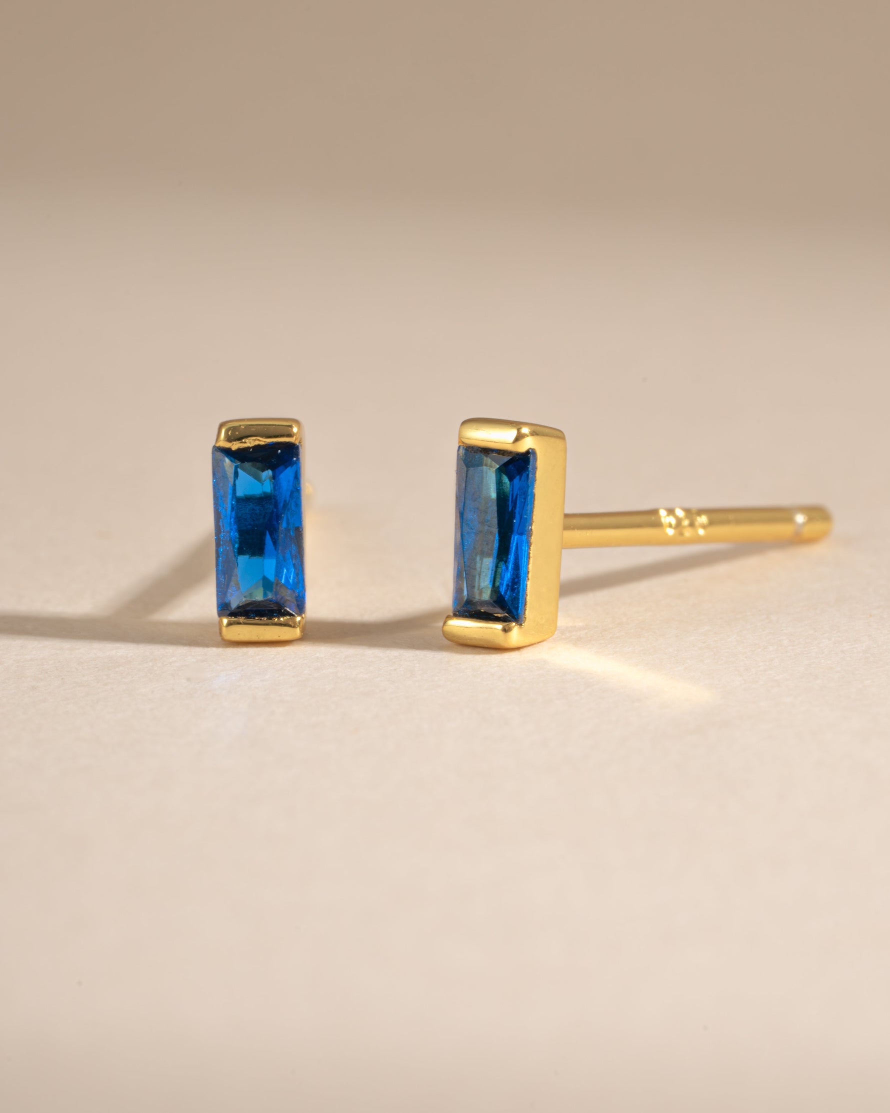 Gold sapphire baguette stud earrings by Sami Jewels, side view showing rectangular blue sapphires in a sleek stud design.