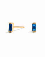 Gold Sapphire Baguette Stud Earrings by Samijewels with sparkling blue sapphires on a white background.