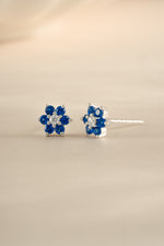 Close-up of Sami Jewels sapphire flower stud earrings with CZ center stone in sterling silver.