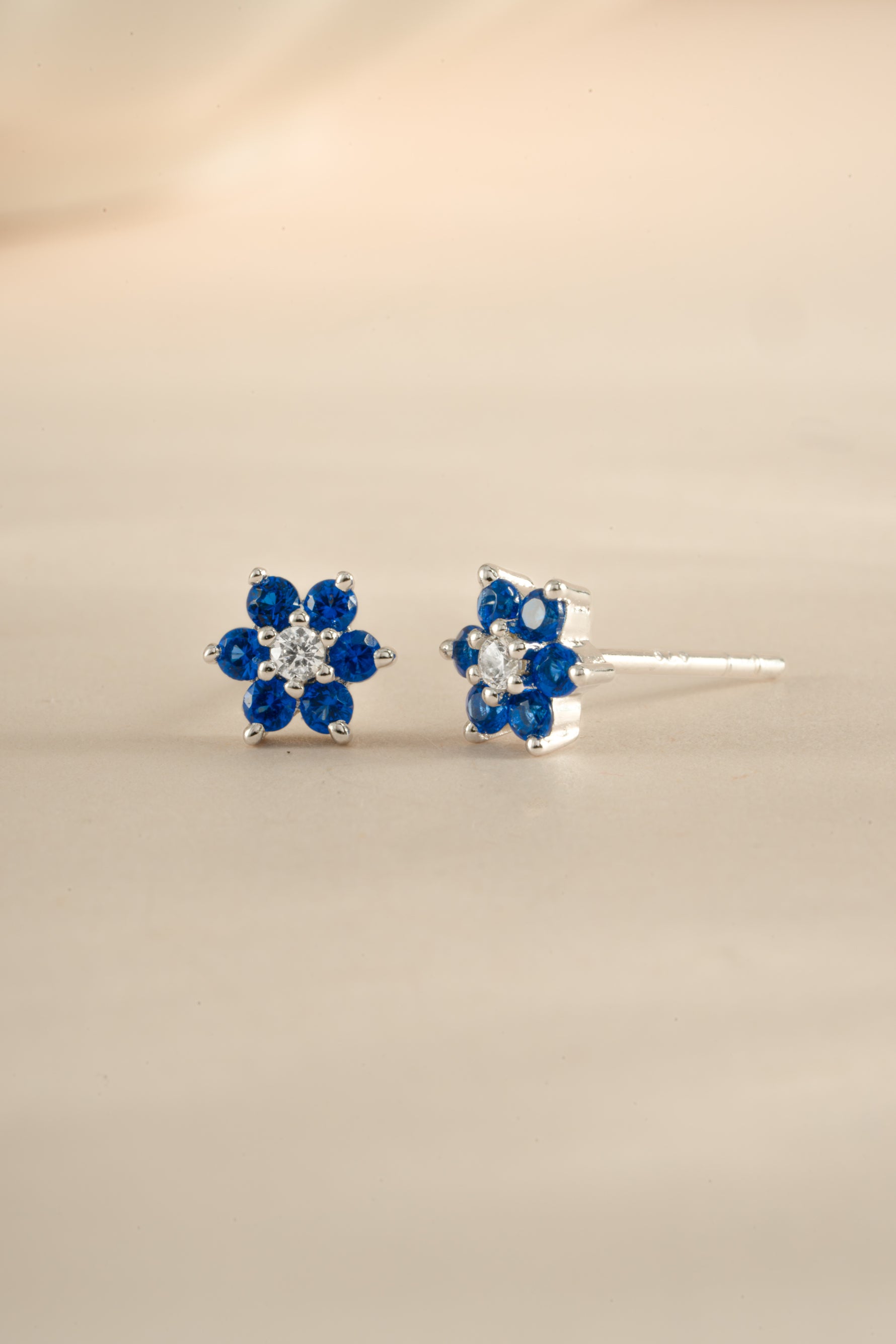 Close-up of Sami Jewels sapphire flower stud earrings with CZ center stone in sterling silver.