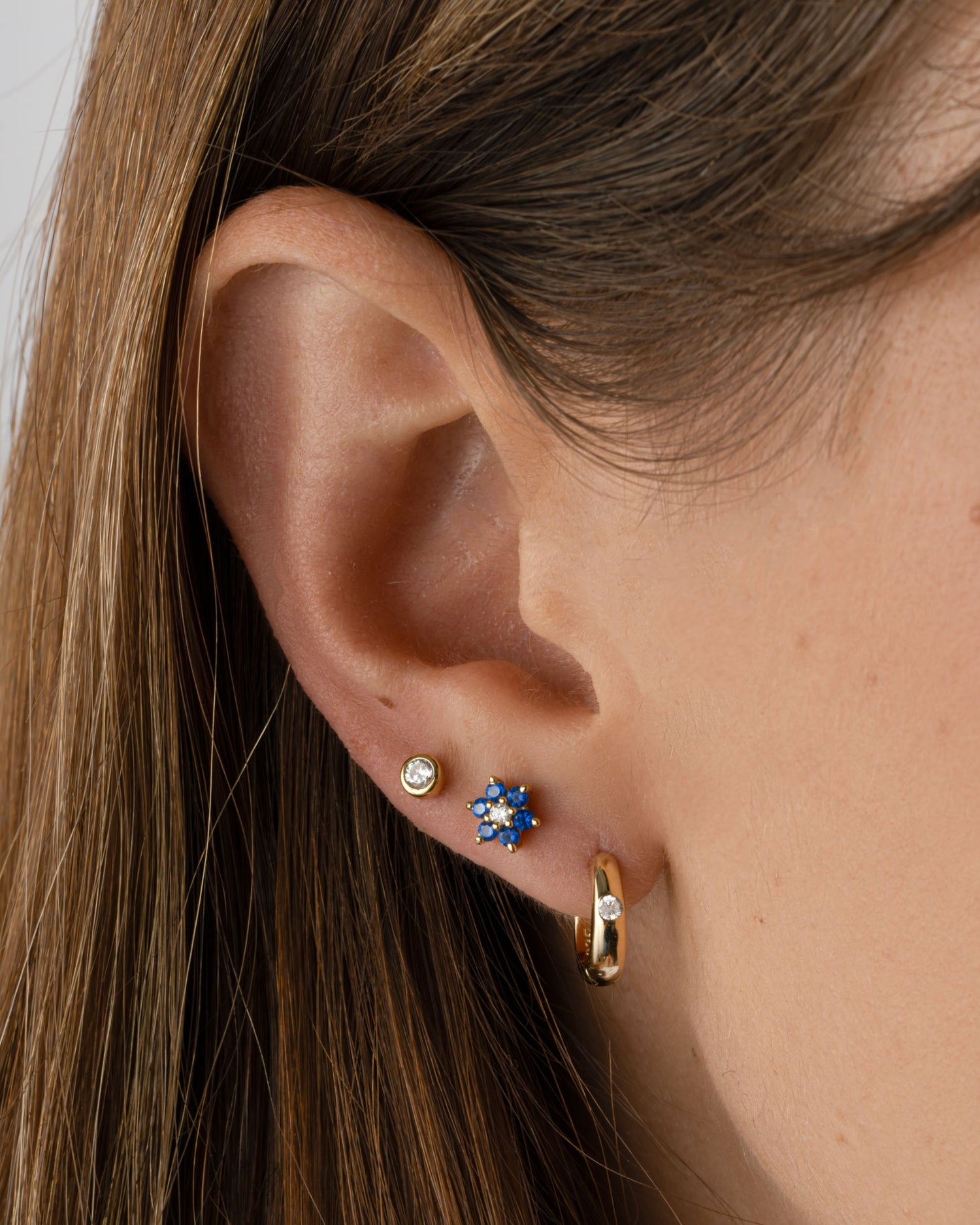 Gold sapphire flower stud earrings with CZ center stone by Sami Jewels, featuring delicate petal design and sparkling accents.