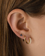Sami Jewels Tiny Sapphire 3 Stone Stud Earrings featuring small blue sapphires set in gold on a model's ears