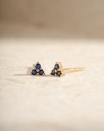 Sami Jewels tiny sapphire three-stone stud earrings with gold settings, showcasing sparkling blue sapphires and a sleek design.