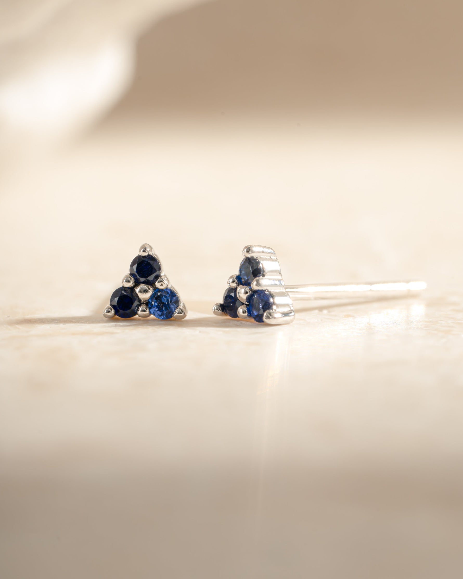 Sami Jewels Tiny Sapphire 3 Stone Earrings featuring sterling silver setting and small blue sapphires in a classic stud design.