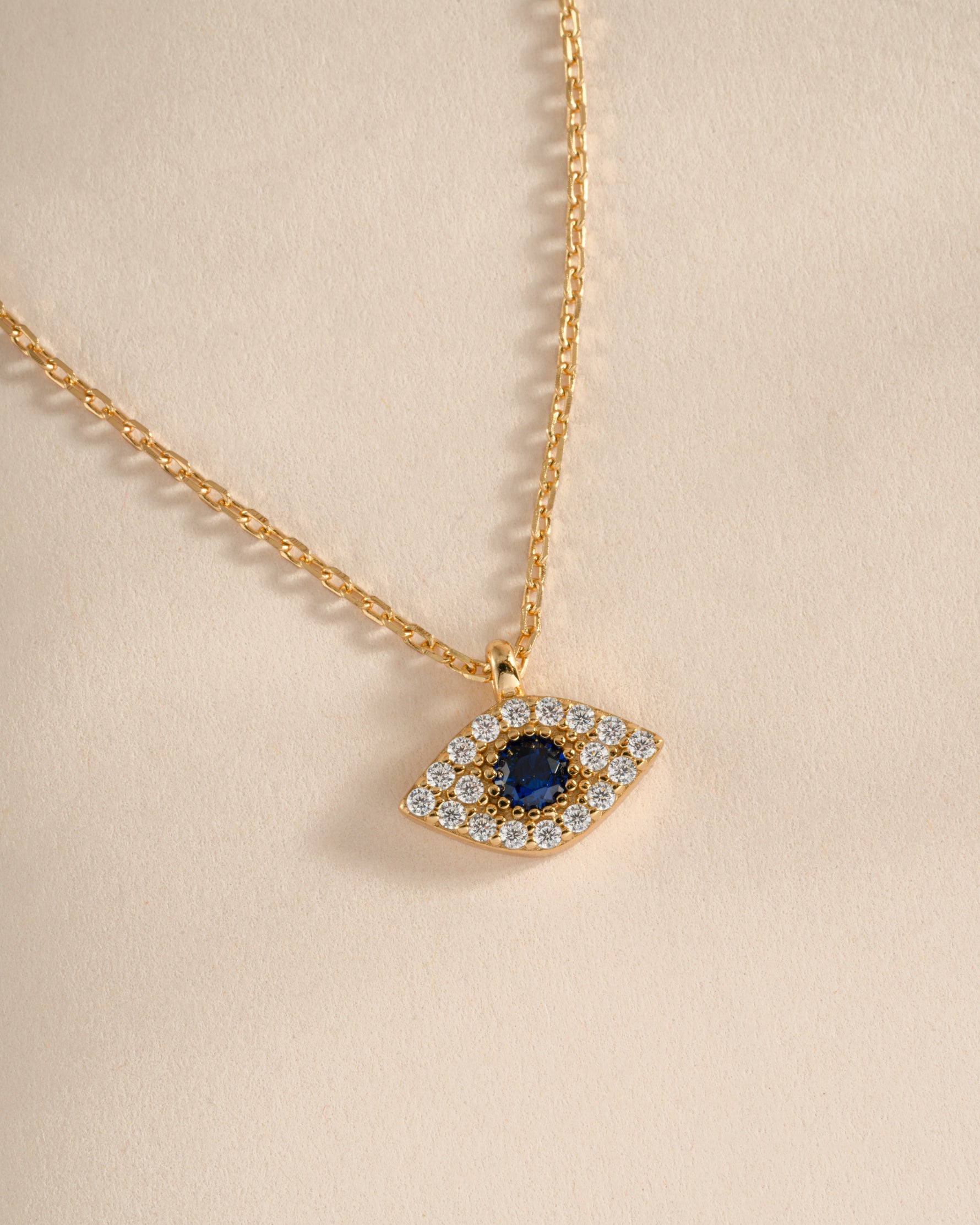 Gold Sapphire Evil Eye Necklace by Sami Jewels featuring a detailed sapphire charm and intricate gold chain.
