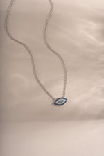 Close-up of Sami Jewels sapphire evil eye necklace featuring a sterling silver chain and a vibrant blue evil eye pendant.