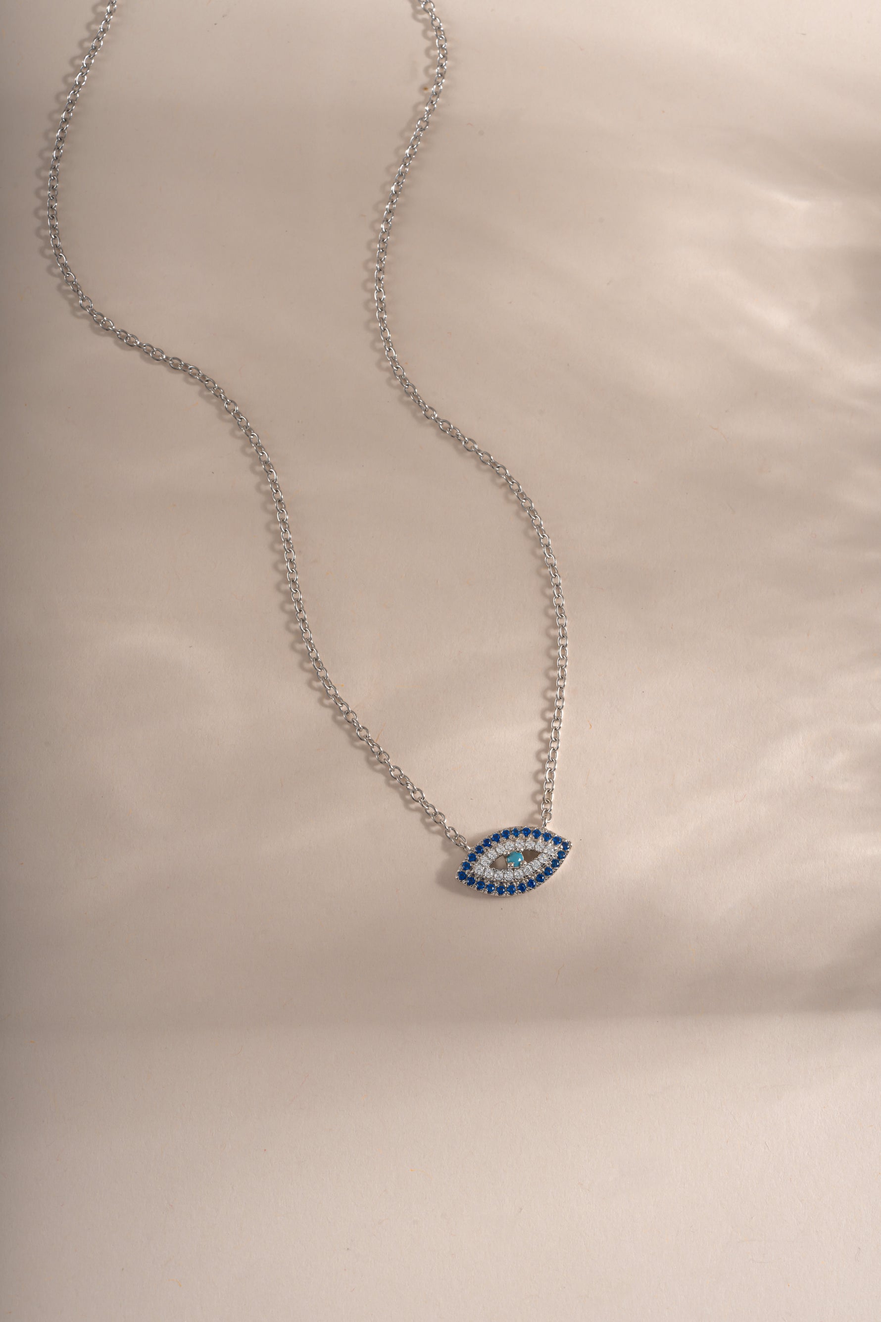 Close-up of Sami Jewels sapphire evil eye necklace featuring a sterling silver chain and a vibrant blue evil eye pendant.
