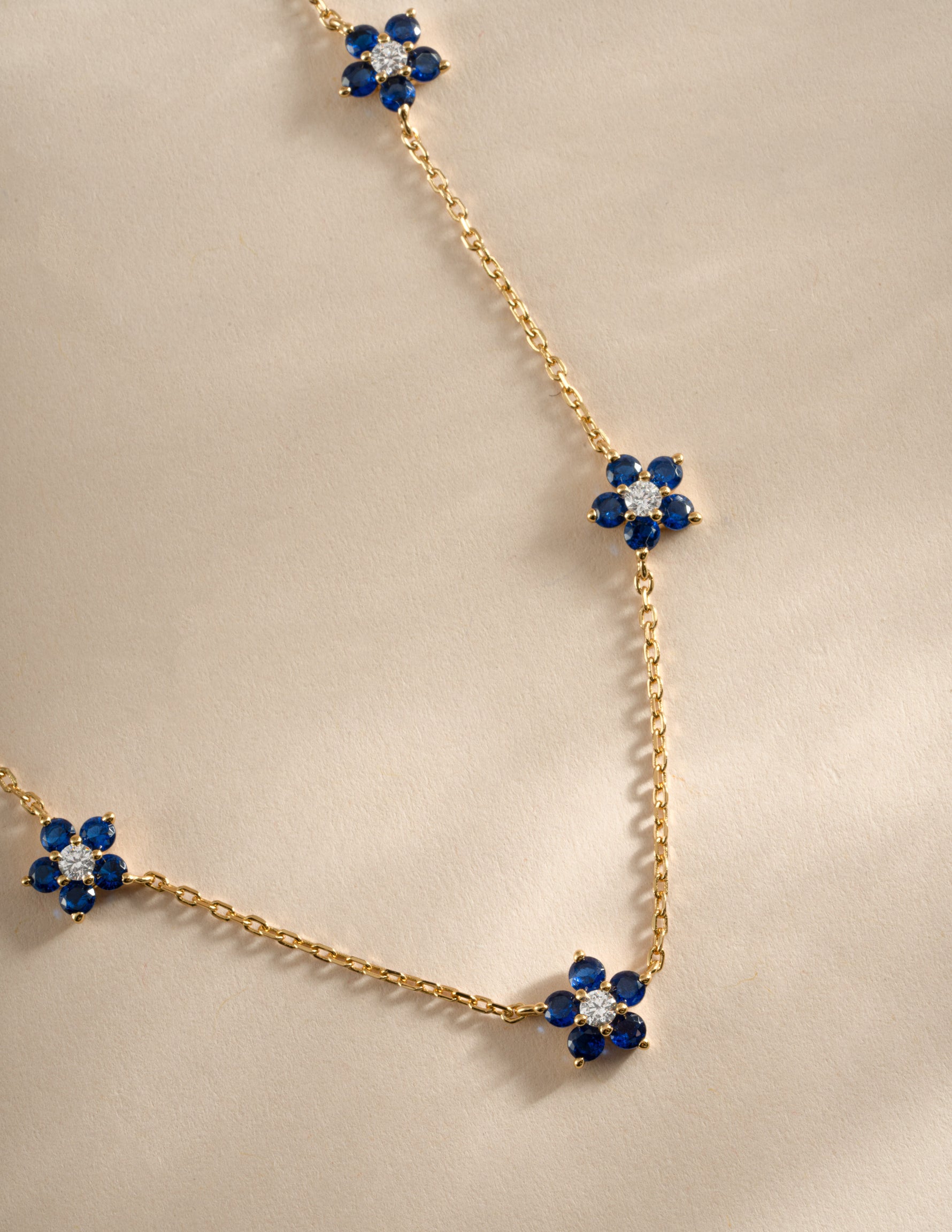 Close-up of SJ Faire Sapphire Flower Necklace featuring a gold chain and a detailed sapphire flower charm.