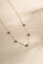 Gold sapphire flower necklace featuring a delicate sapphire flower charm, designed by SJ Faire.