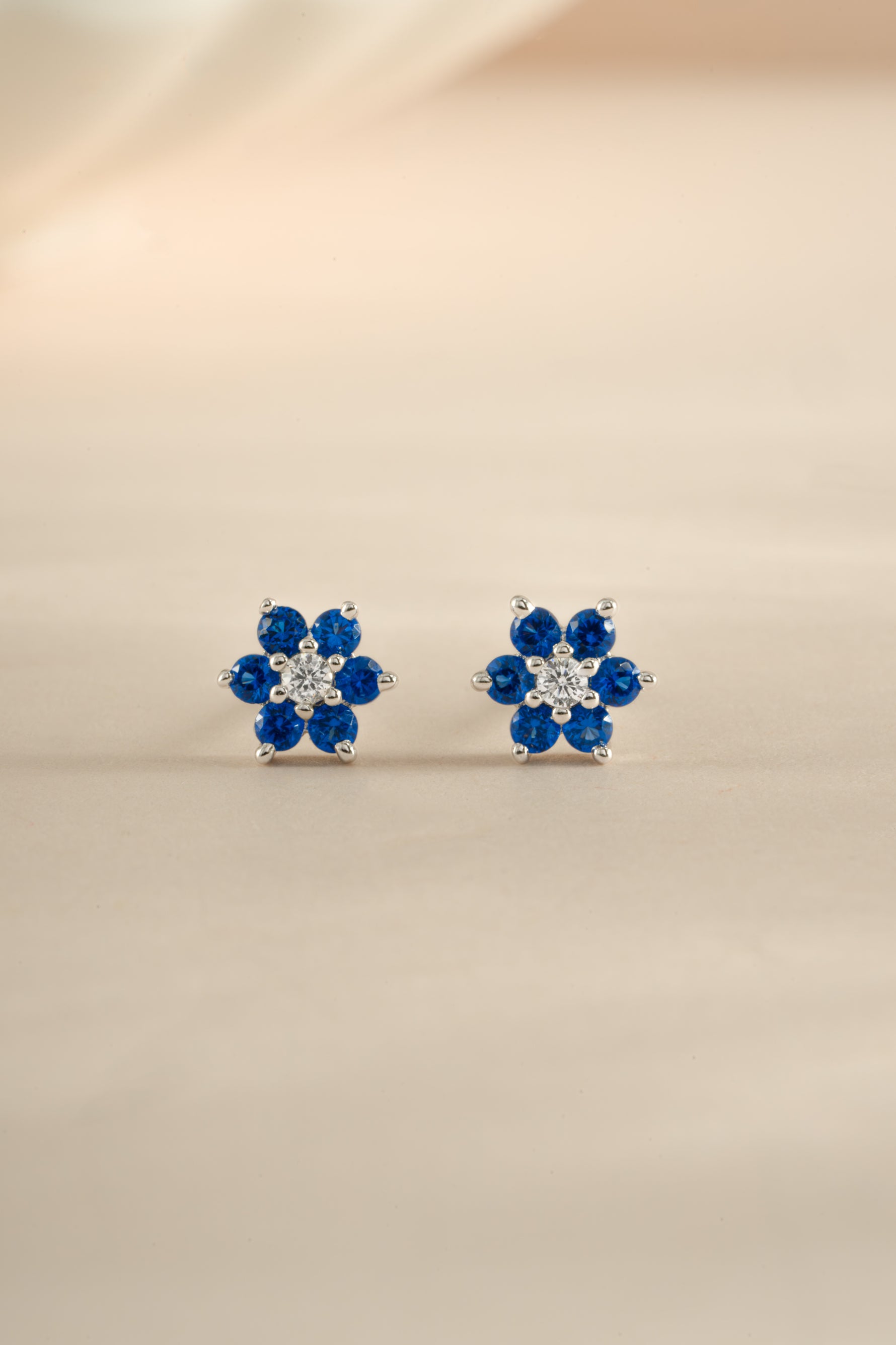 Sami Jewels sapphire flower stud earrings with CZ center stone in sterling silver, front view showing detailed floral design