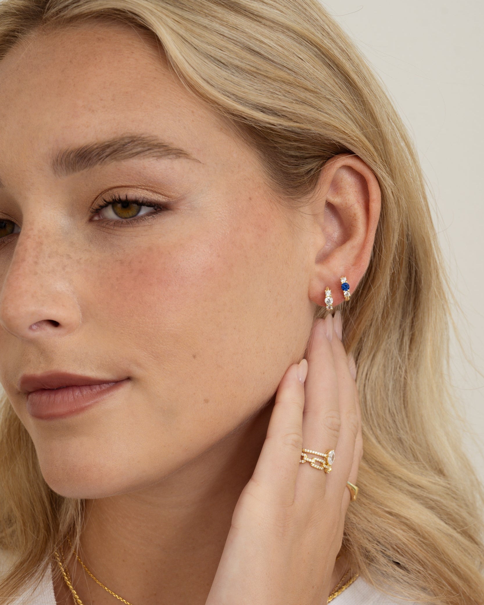 sapphire three stone huggie hoop earring on model with gold jewelry