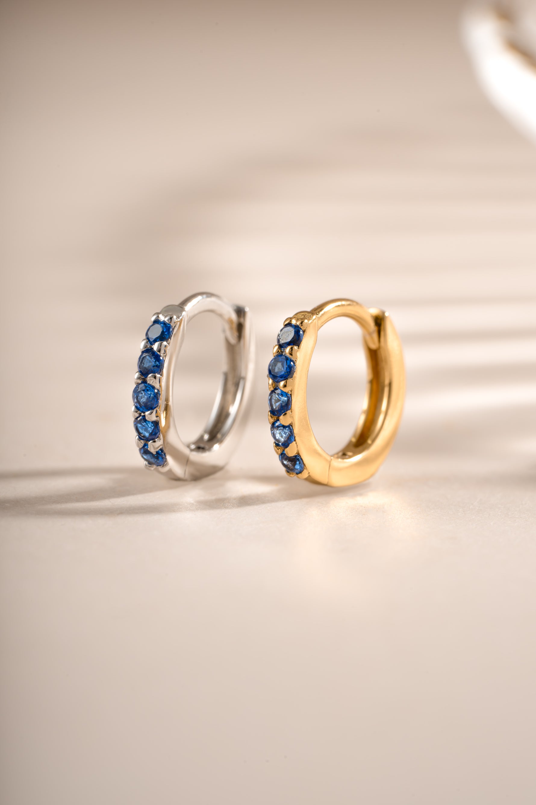 Sapphire-studded 7mm sterling silver and gold earrings by Sami Jewels, featuring elegant sapphire gemstone hoops.