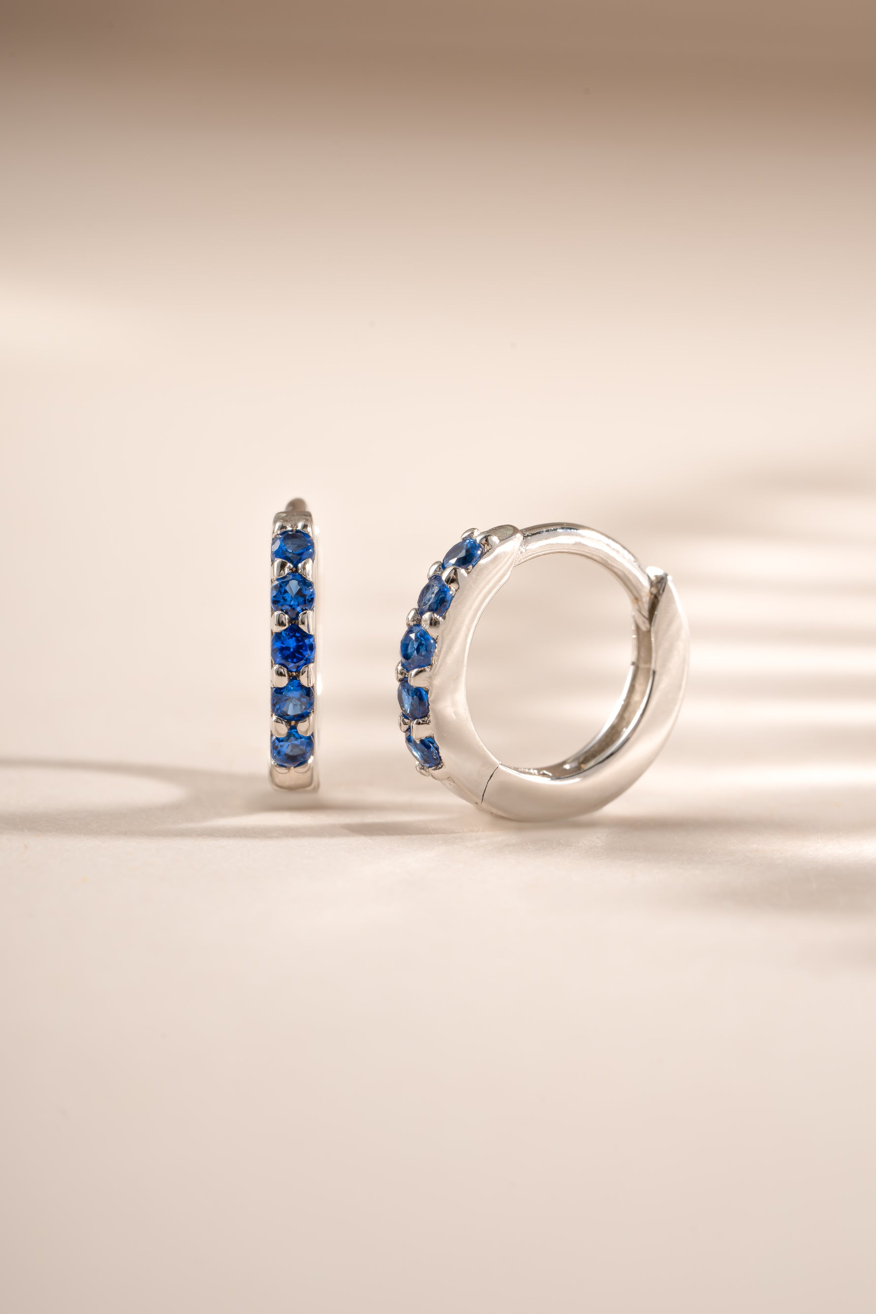 Sapphire studded sterling silver huggie earrings by Sami Jewels featuring 7mm round sapphires.