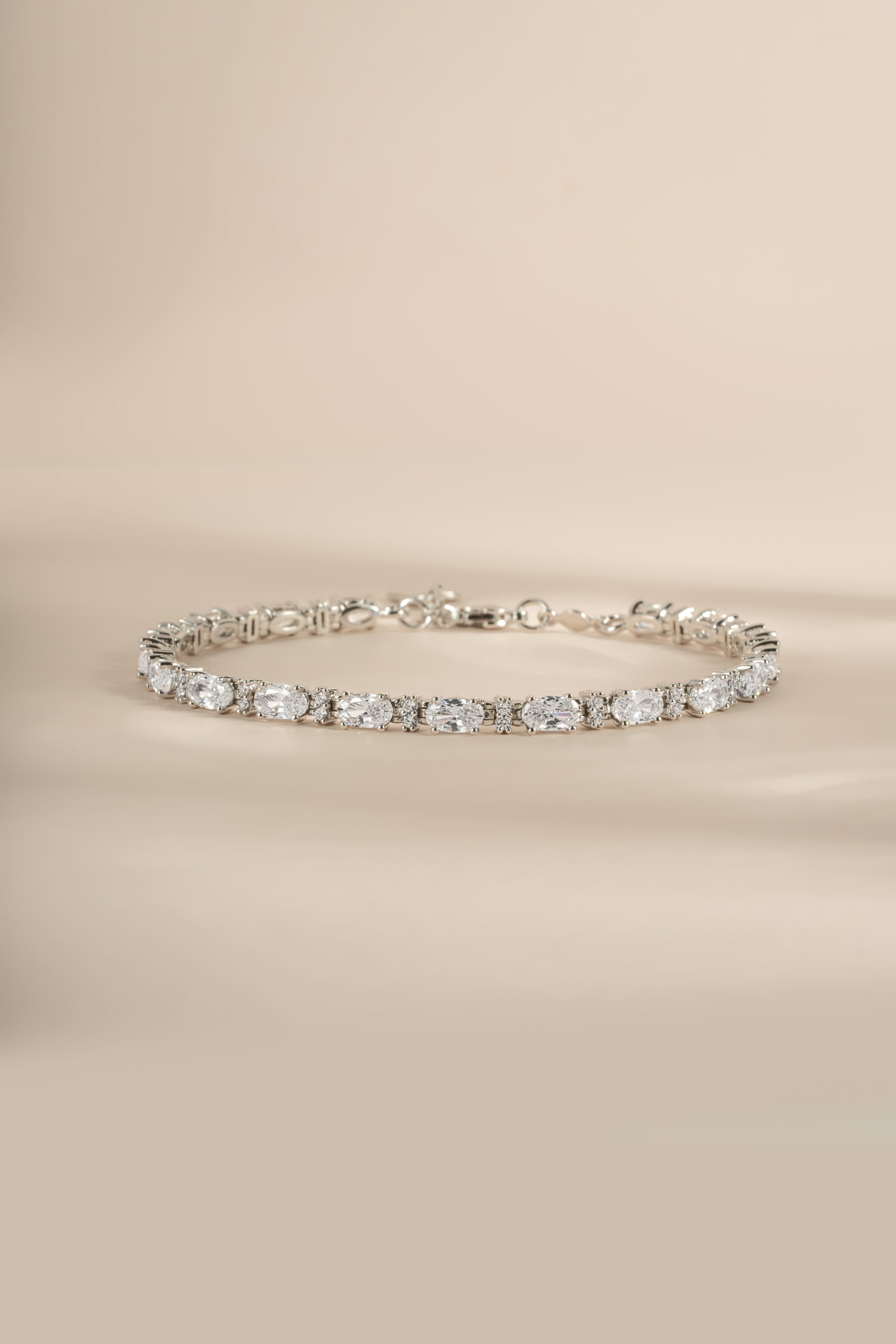 A silver tennis bracelet with clear oval and round cubic zirconia stones.