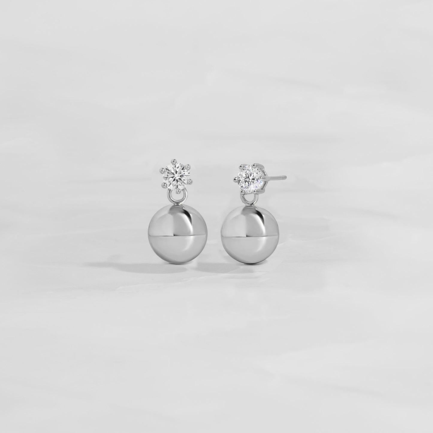 close up of diamond stud earrings with small silver ball earrings