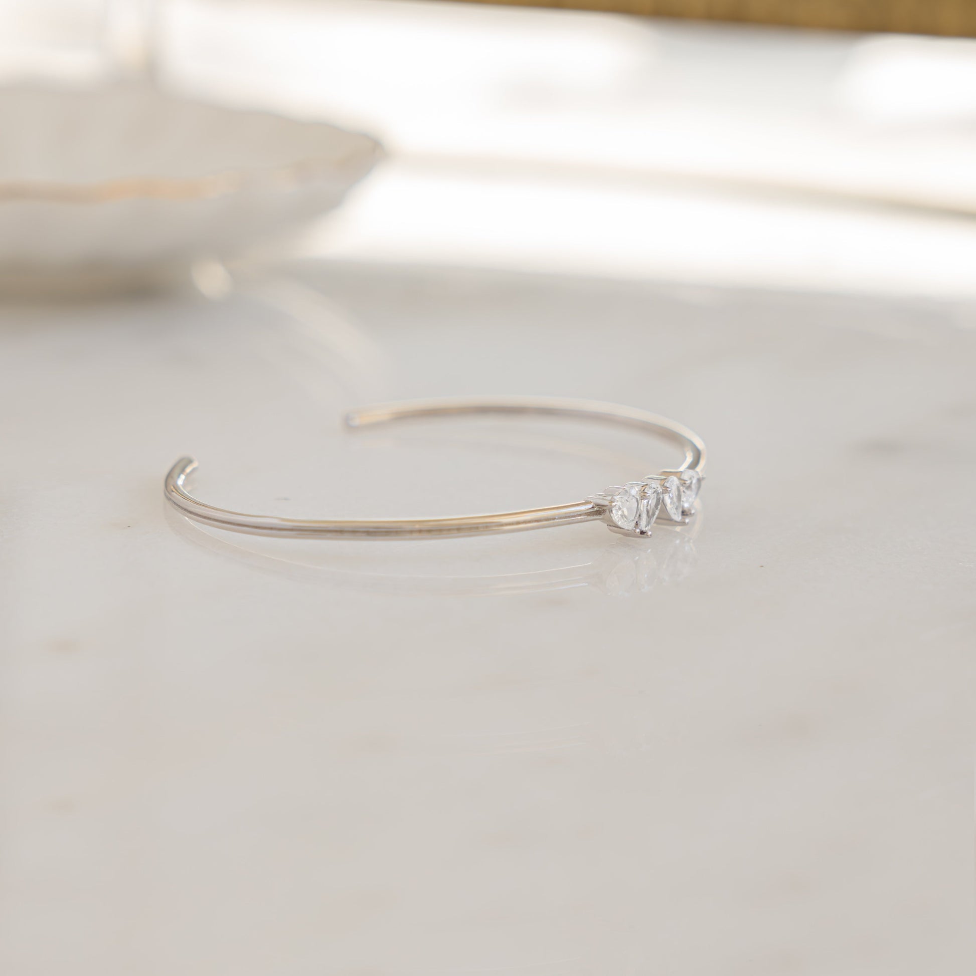 a side profile of a thin silver bangle with stones