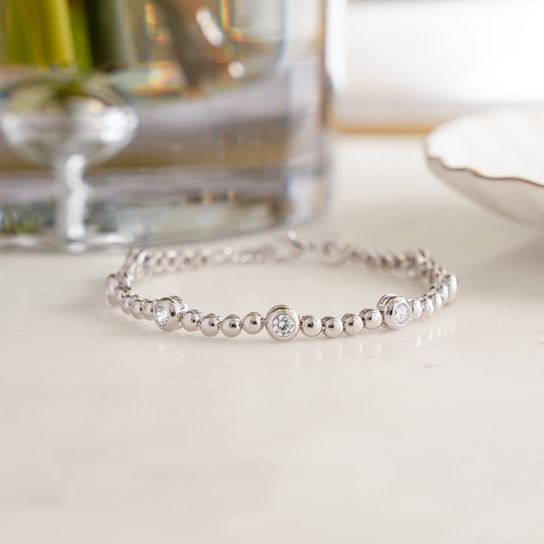 Flat lay of tennis bracelet with bezel diamonds and beads, in silver.