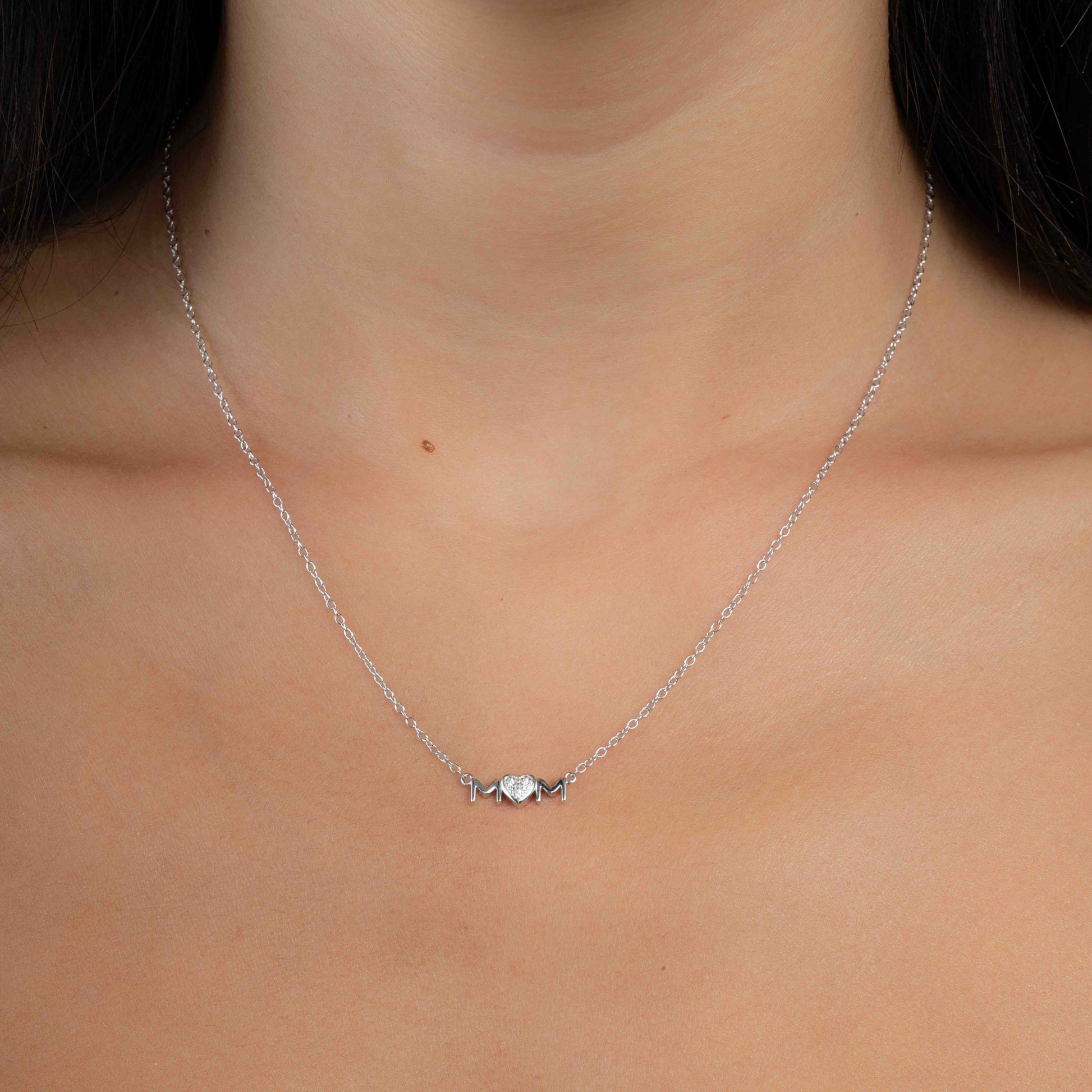 Model wearing silver pendant necklace with "MOM" pendant 