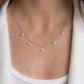 model wearing a sterling silver charm necklace consisting of 5 small four clear clover charms