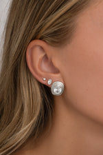 Close-up of a silver oval bezel statement stud on an ear, with smaller oval and round studs.