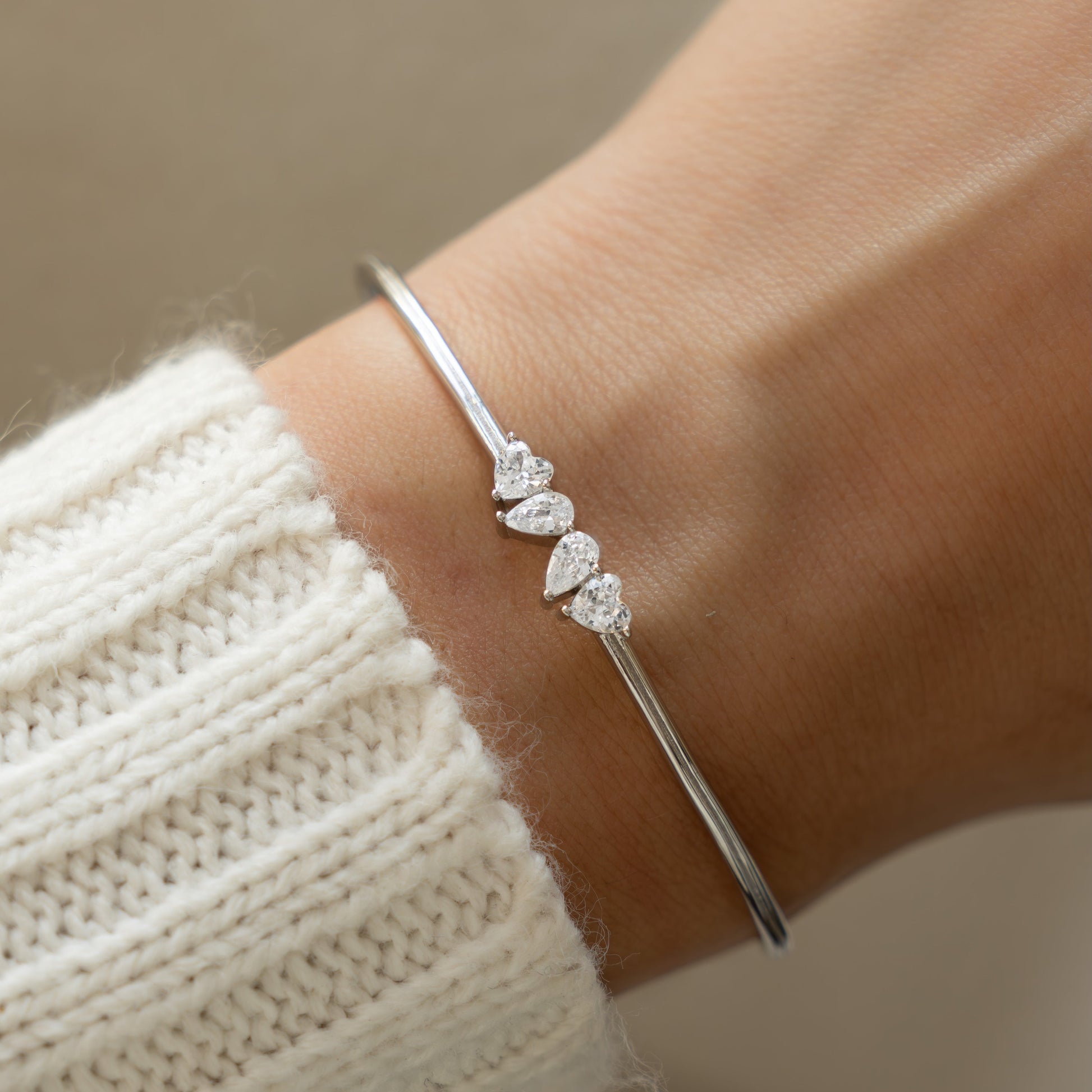 a woman's wrist wearing a silver cuff bracelet that is adjustable and made of cubic zirconia stones. 