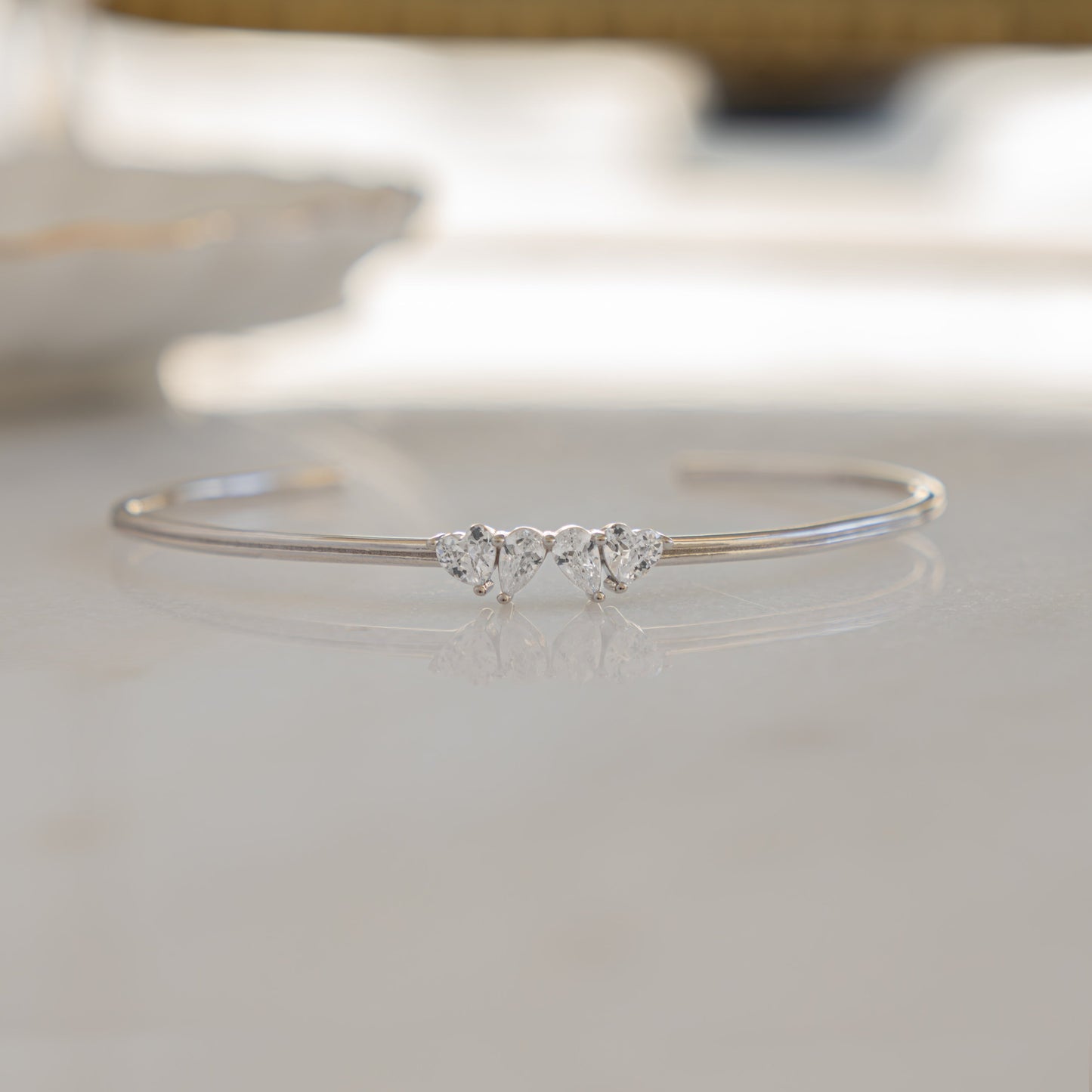 a close up of a dainty silver bracelet that is design to be adjustable and cuff design