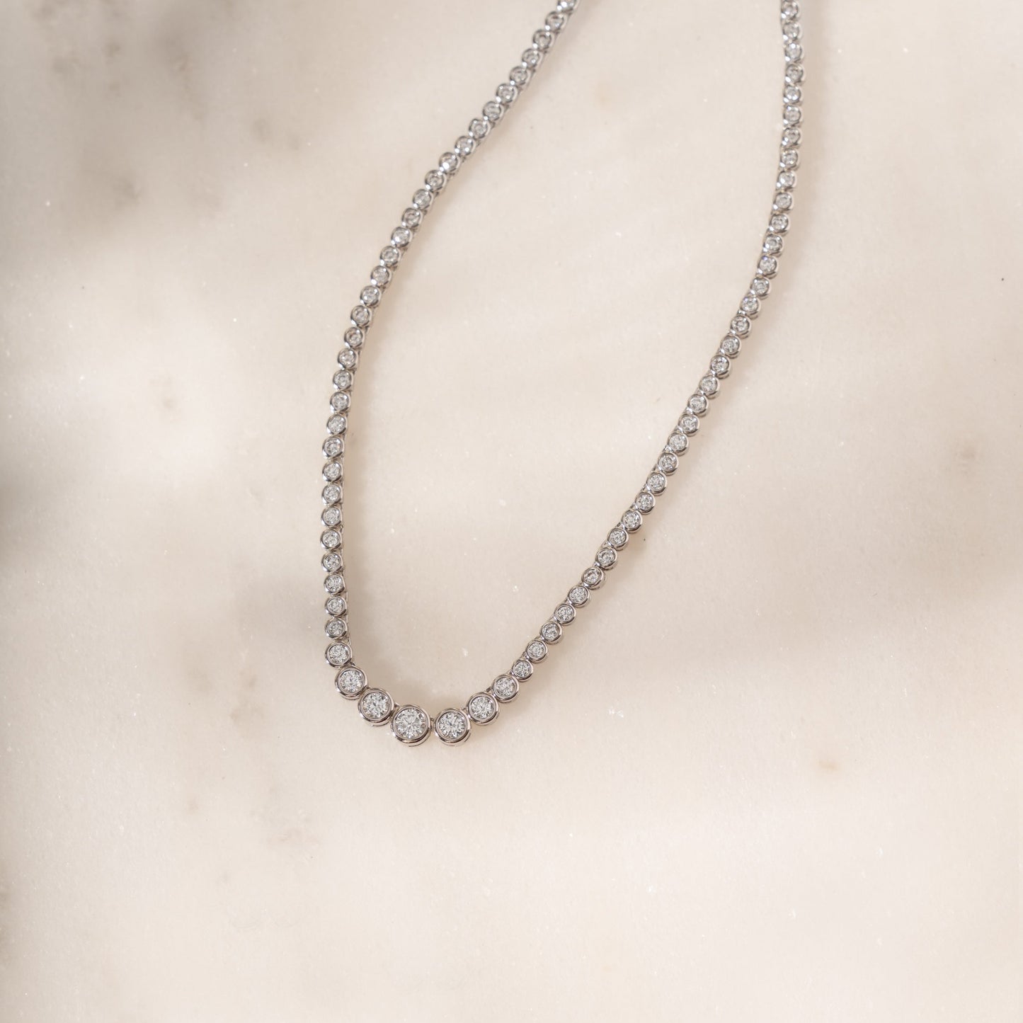 flat lay of a silver tennis choker featuring a gradient diamond design.